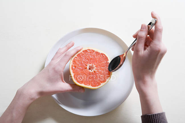 Junge Frau isst Grapefruit — Stockfoto