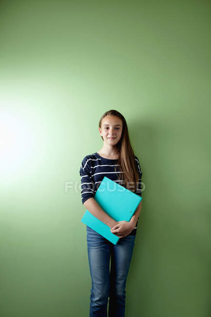 Schülerin hält Ringbuch vor grünem Hintergrund — Stockfoto