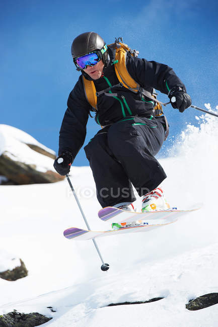 Skieur sautant de la pente enneigée — Photo de stock