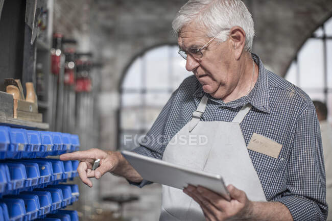 Kapstadt, Südafrika, älterer Handwerker beim Zählen mit einem Block in der Hand — Stockfoto
