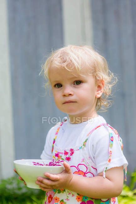 Girl holding flower in bowl outdoors — Stock Photo