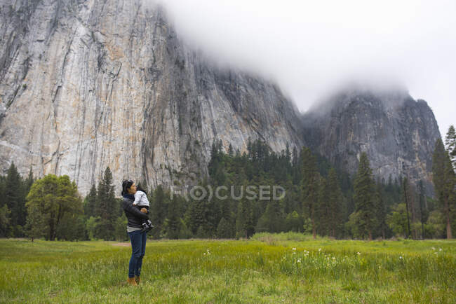 Mulher adulta média carregando filha criança no prado, Parque Nacional de Yosemite, Califórnia, EUA — Fotografia de Stock