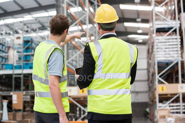 Deux hommes en entrepôt, un pointant du doigt — Photo de stock
