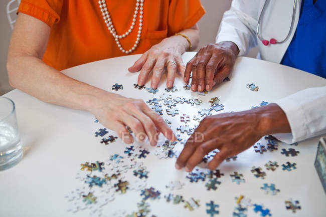 Donna anziana e medico con puzzle — Foto stock