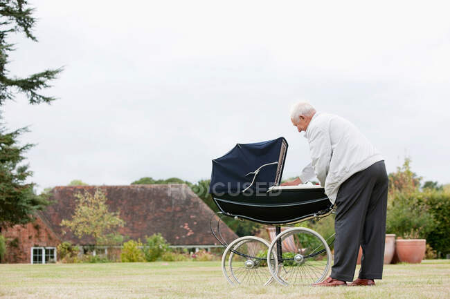 Grandfather looking at baby in pram — Stock Photo
