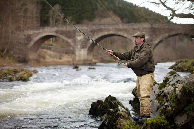Человек ловит лосося в реке — стоковое фото