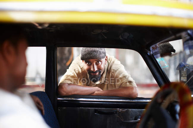 Smiling man leaning in taxi cab window — Stock Photo
