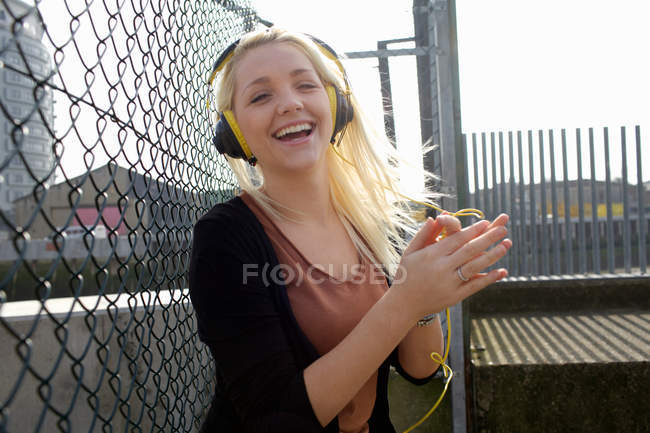 Mujer sonriente escuchando auriculares - foto de stock