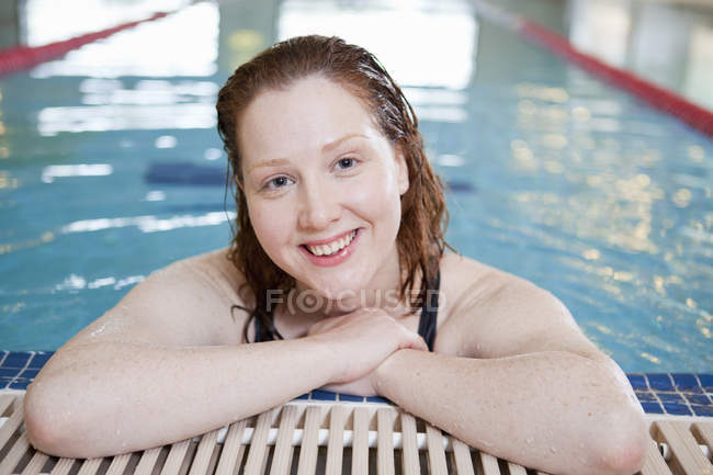 Femme souriante dans la piscine intérieure — Photo de stock