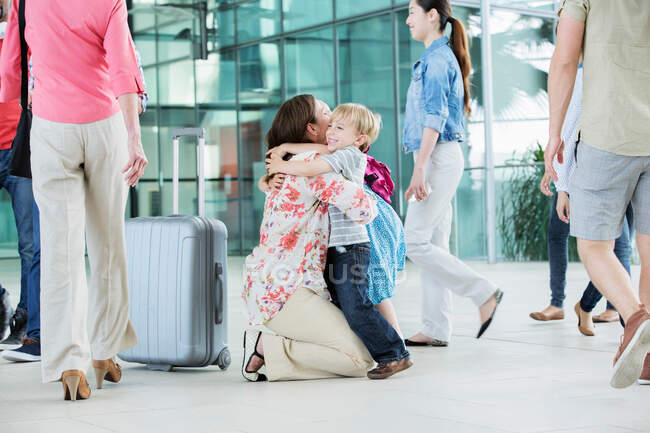 Mère embrassant les enfants à l'aéroport — Photo de stock