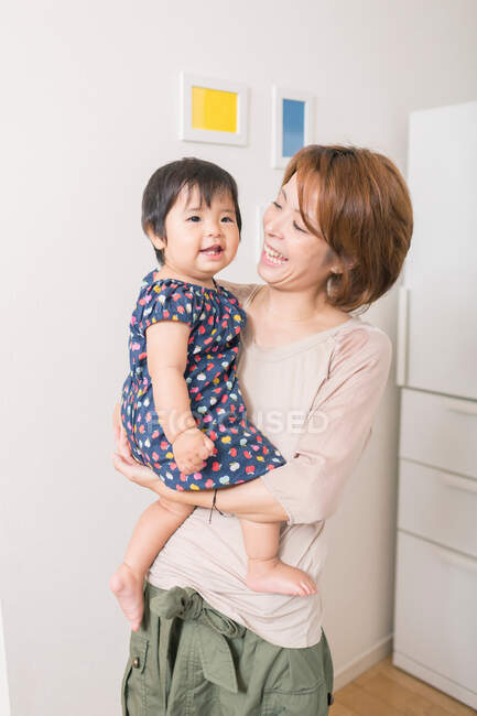 Madre sorridente al bambino in braccio — Foto stock