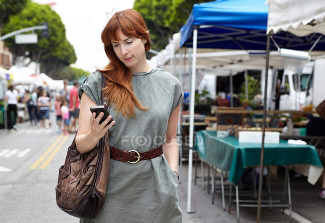 Mitte erwachsene Frau schaut in der Stadt aufs Handy — Stockfoto