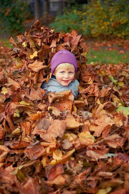 Chica jugando en hojas de otoño - foto de stock