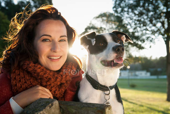 Mujer sentada con perro en el banco del parque - foto de stock