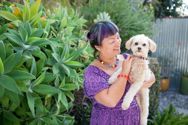 Mulher adulta média ao ar livre, segurando cão — Fotografia de Stock