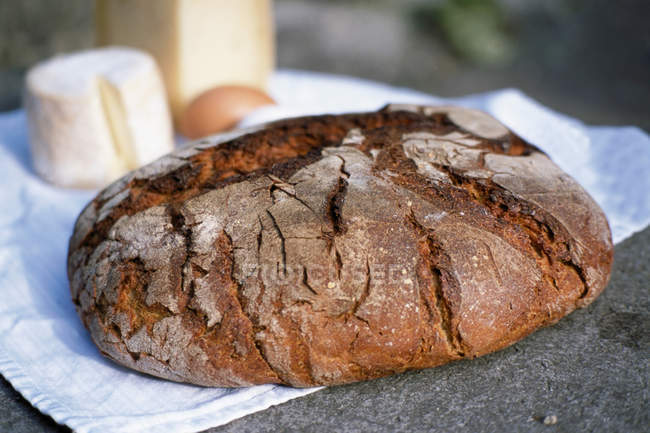 Close up shot of wholegrain bread loaf on tea towel — Stock Photo