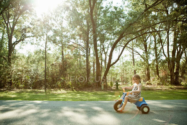 Menina equitação brinquedo triciclo na estrada rural — Fotografia de Stock