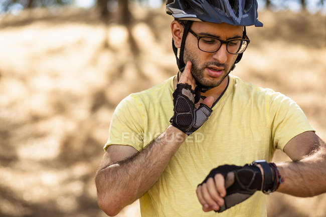Joven ciclista de montaña comprobando smartwatch, Mount Diablo, Área de la Bahía, California, EE.UU. - foto de stock
