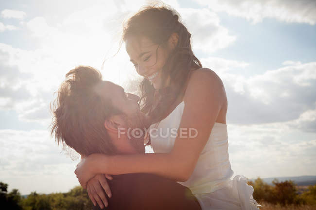 Recién casados novio sosteniendo novia al aire libre - foto de stock