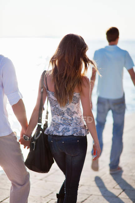 Vista trasera de pareja caminando de la mano al aire libre - foto de stock