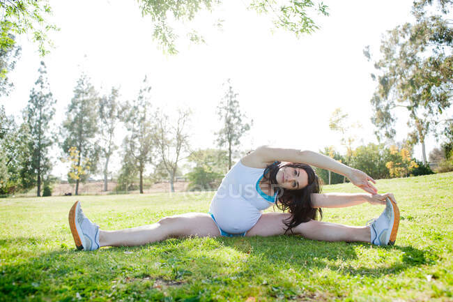Pregnant young woman stretching to touch toes — Stock Photo