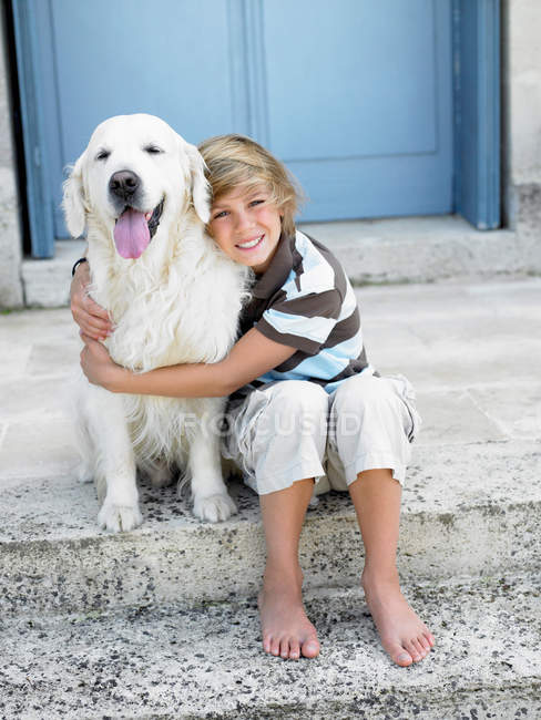 Хлопчик з собакою на порозі — стокове фото