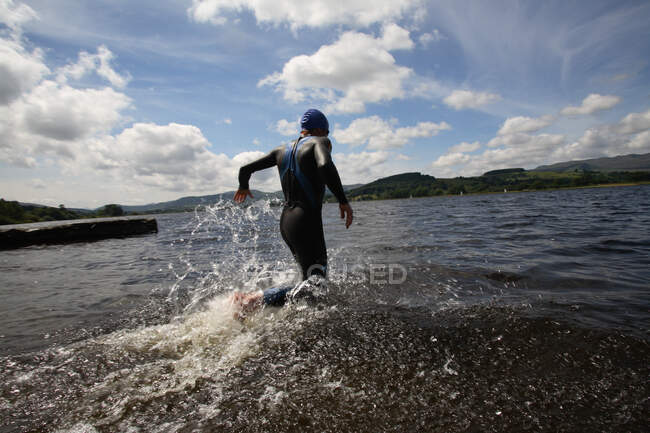 Triathlete swimmer running into water — Stock Photo