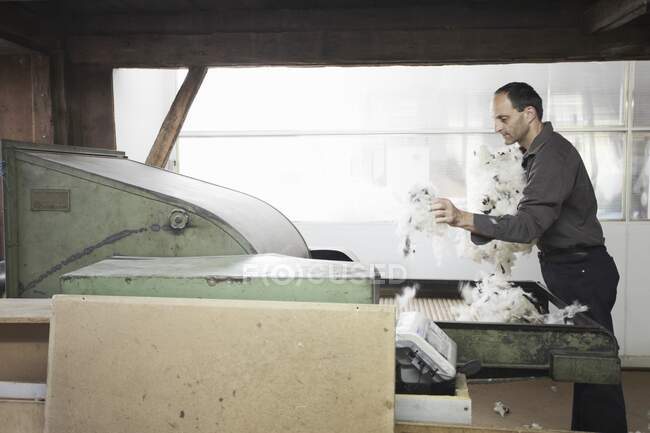 Man adding fleece to machine in wool factory — Stock Photo