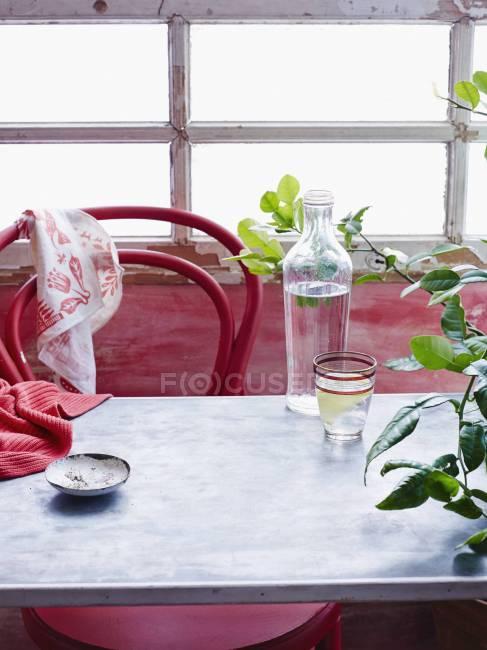 Mesa de restaurante com garrafa de água, vidro e guardanapo — Fotografia de Stock