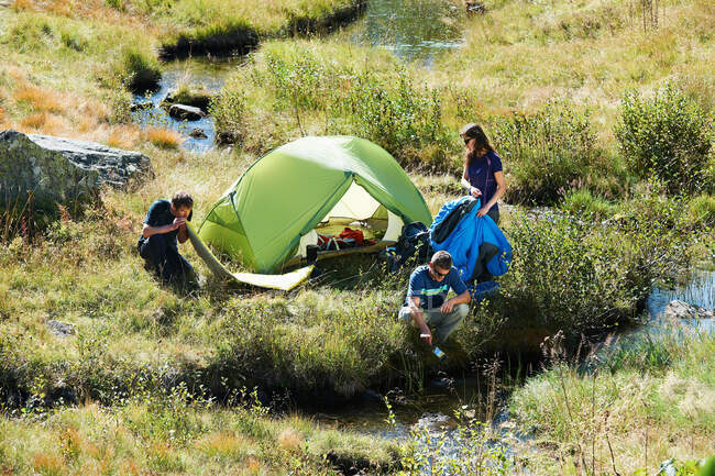 Tres personas acampando por arroyo, Chamonix, Alta Saboya, Francia - foto de stock
