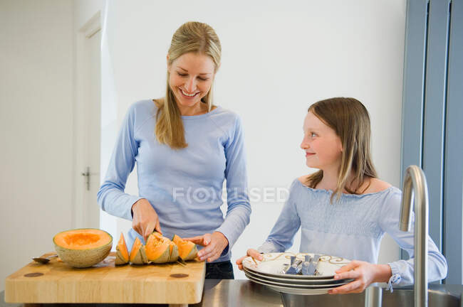 Madre e hija preparando melón - foto de stock
