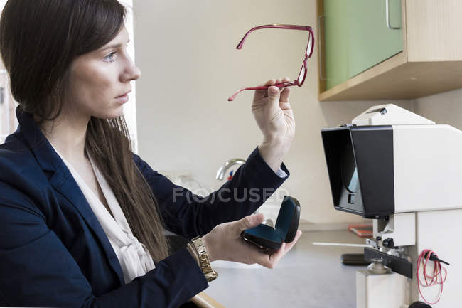 Side view of optician looking at pair of eye glasses — Stock Photo