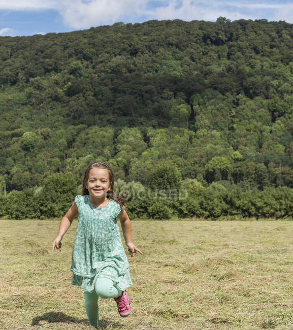 Menina correndo no campo olhando para a câmera sorrindo, Porta Westfalica, Renânia do Norte Westphalia, Alemanha — Fotografia de Stock