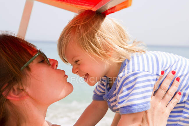 Мать целует ребенка на пляже — стоковое фото