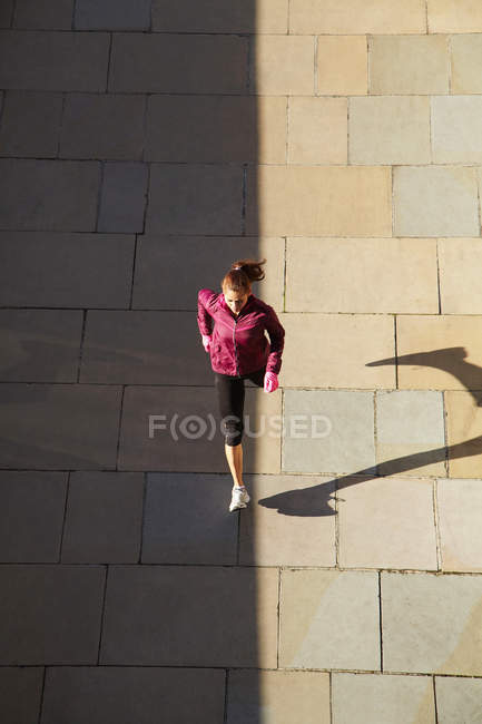 Над головой вид женщины, бегущей по городской улице — стоковое фото