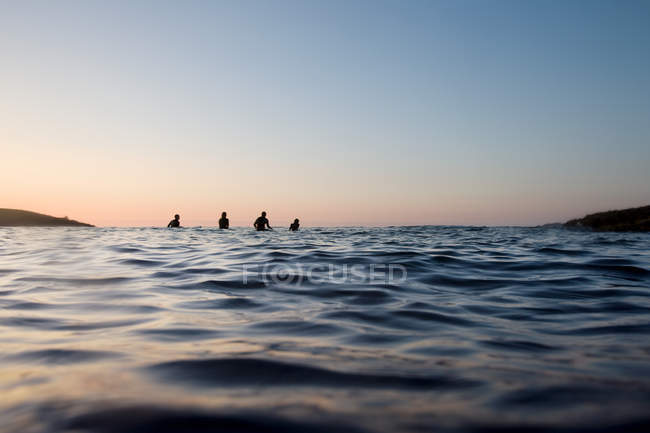 Чотири людини сидять на дошках для серфінгу — стокове фото