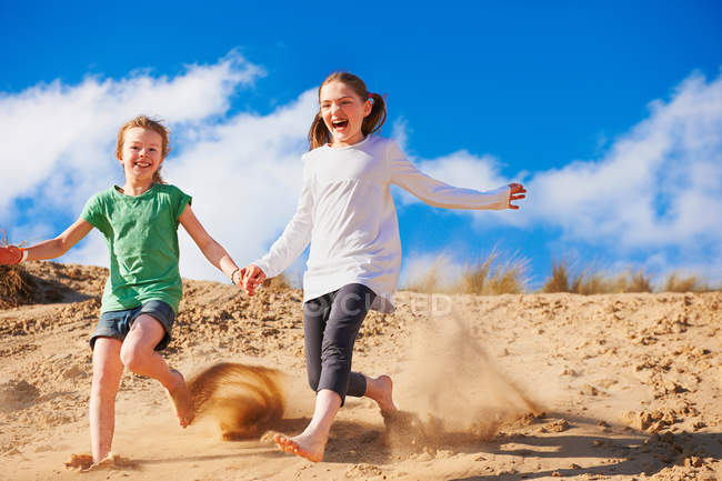 Дві дівчини біжать на піщаній дюні — стокове фото