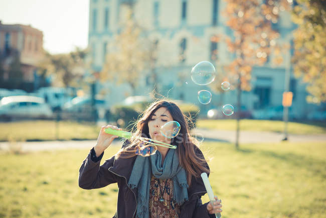 Mid adult woman blowing bubbles in park — Stock Photo