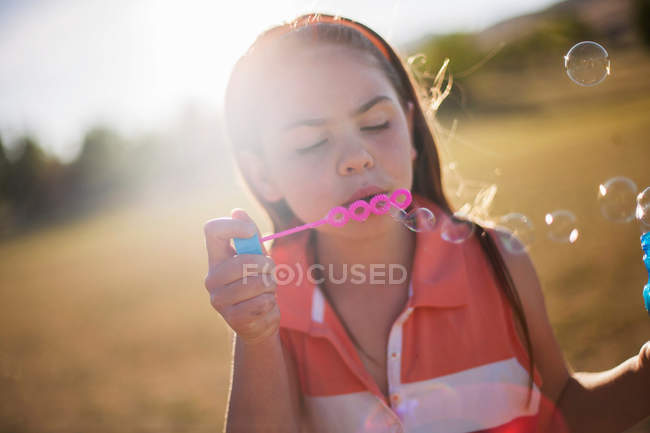 Дівчина дме бульбашки на відкритому повітрі — стокове фото