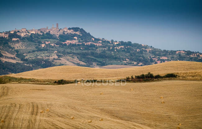 Harvested fields and town on hilltop — Stock Photo