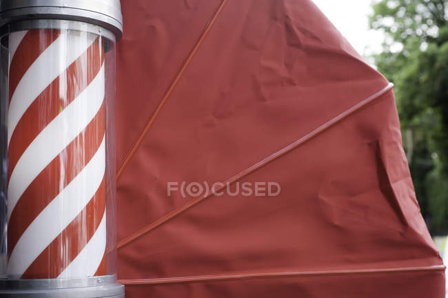 Vista lateral de los peluqueros poste y toldo rojo - foto de stock