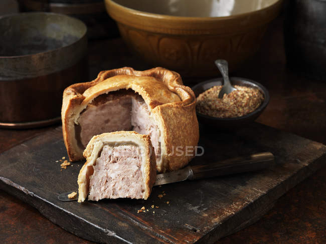 Siced pork pie with wholegrain mustard on wooden cutting board — Stock Photo