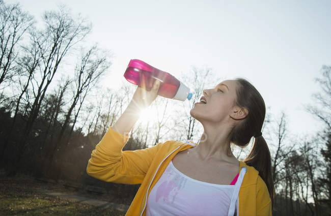 Молодая бегунья пьет воду на открытом воздухе — стоковое фото