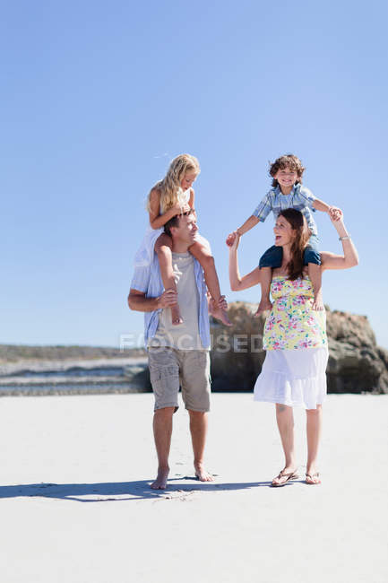 Parents carrying children on shoulders — Stock Photo