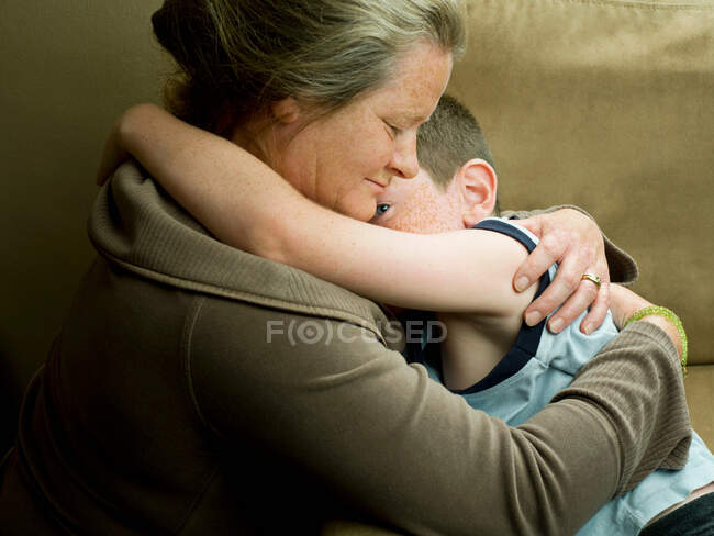 Una madre abrazando a su hijo - foto de stock