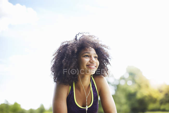 Jeune femme écoutant des écouteurs dans le parc — Photo de stock