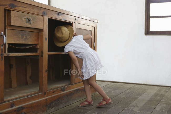 Menina olhando embaixo armário — Fotografia de Stock