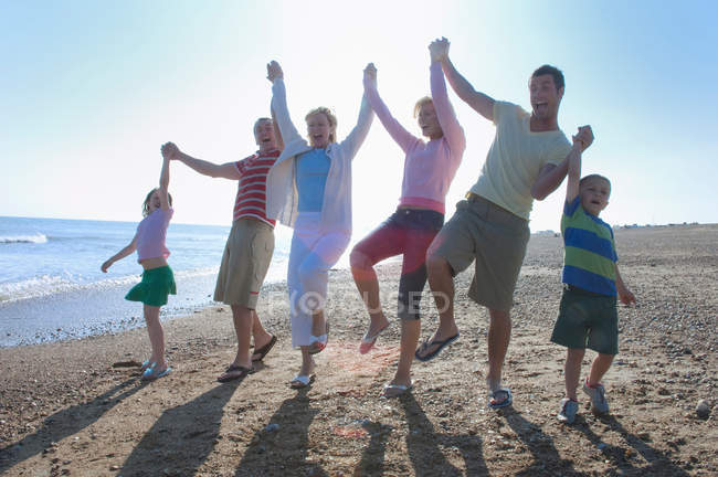 Familia sosteniendo las manos en la playa - foto de stock