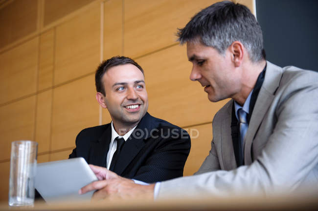 Бизнесмены за столом за планшетным компьютером — стоковое фото