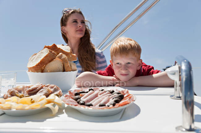 Frau und Junge essen Mittagessen auf Jacht — Stockfoto